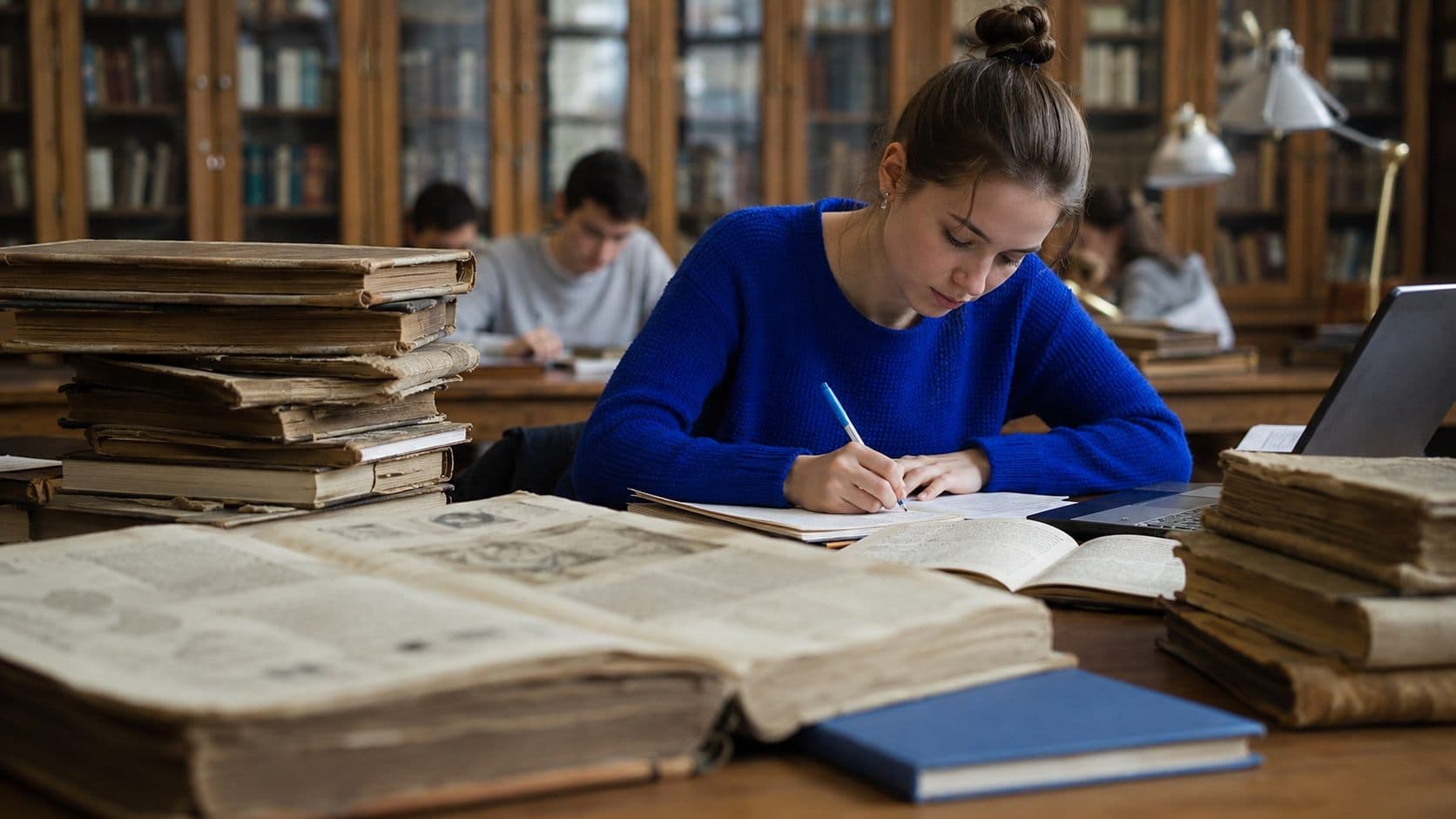 Студентка работает с рукописями и старинными книгами в читальном зале